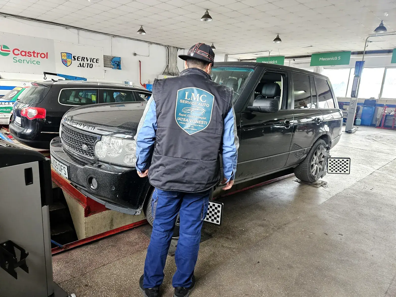 Mecanic LMC verificând un Range Rover ridicat pe elevator, în atelierul din Voinești